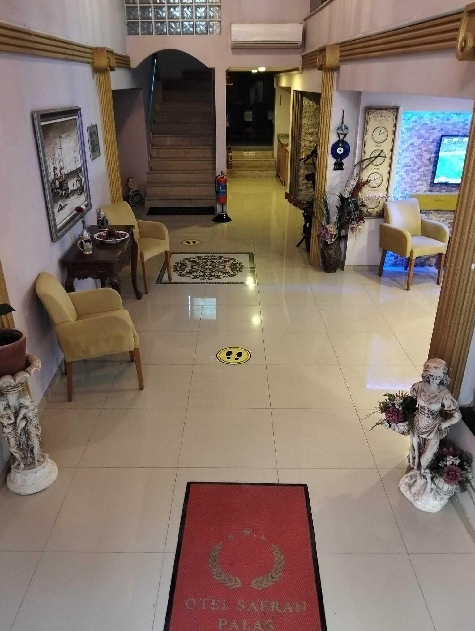 A hotel lobby with a reception desk, seating area, and a staircase leading to upper floors.