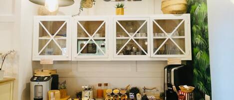 A kitchen with white cabinets, a coffee machine, and various kitchen items on the counter.