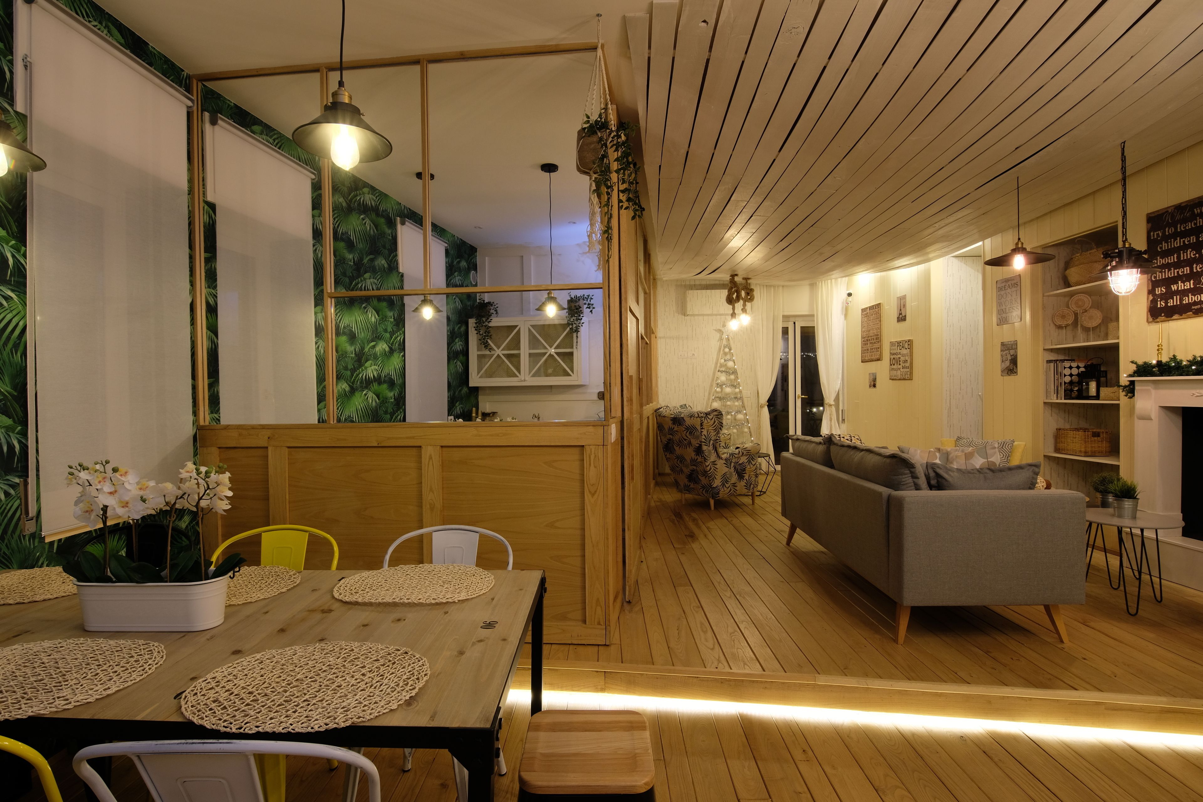 A cozy living room with a sofa, a dining table with placemats, and a wooden floor.