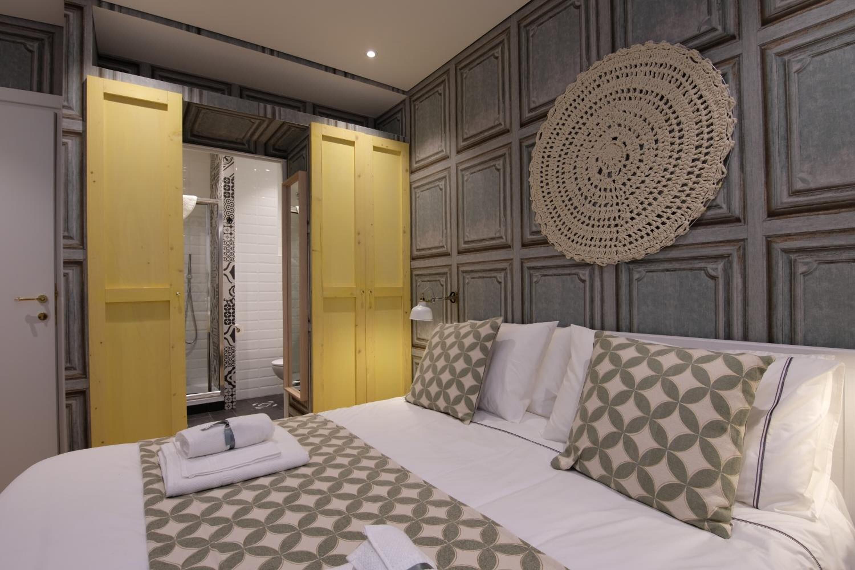A hotel room with a bed, a yellow door, a shower, and a decorative wall piece.