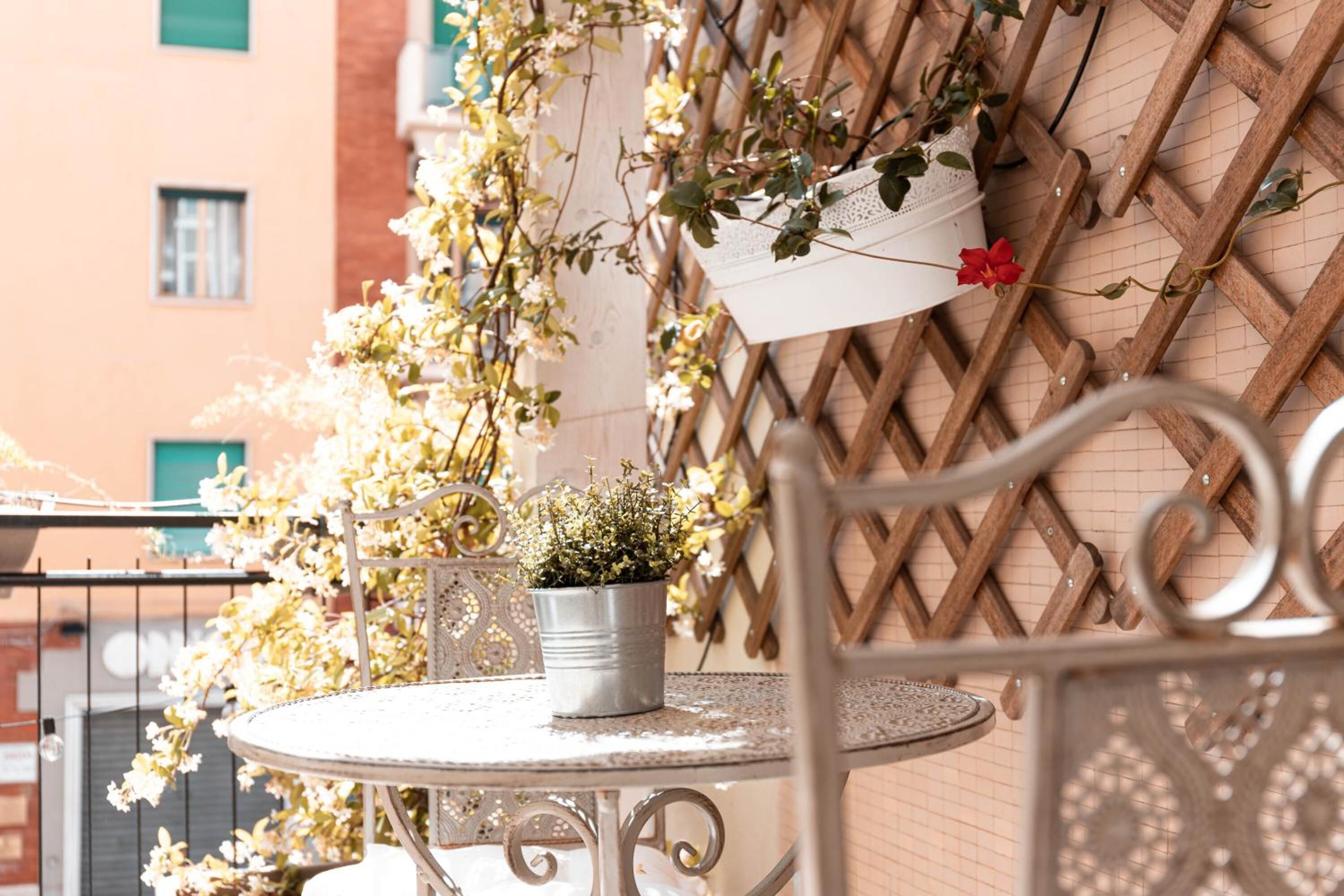 A round metal table with a potted plant and a metal chair.