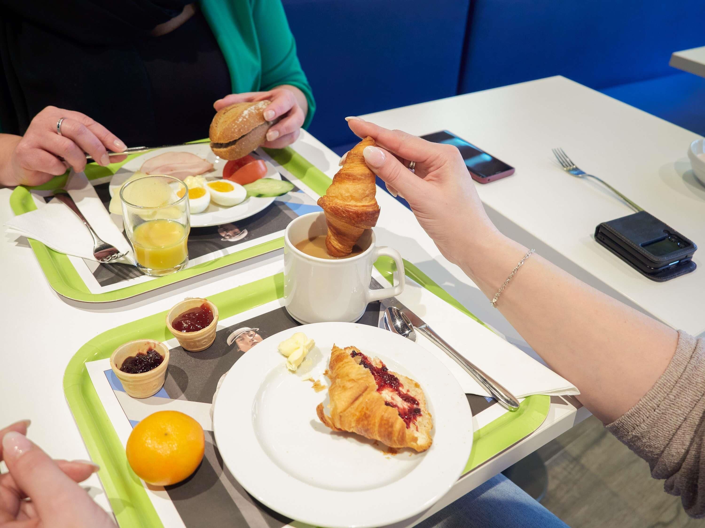 A breakfast setting with plates of food, a glass of orange juice, and a cup of coffee.
