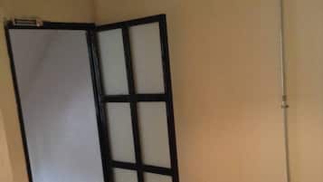 A room with a bed, a white wall, and a door with a black frame.