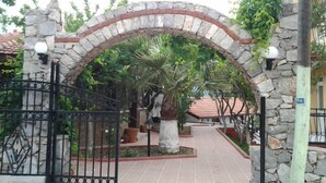A stone archway leading to a courtyard with a palm tree and potted plants.