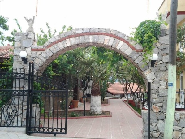 A stone archway leading to a courtyard with a palm tree and potted plants.