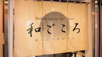 Opastekyltti modernille japanilaistyyliselle hostellille, jossa on nimi «WAGOKORO», kirjoitettuna sekä japaniksi että englanniksi.