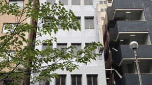 Un edificio de varios pisos con fachada blanca y múltiples ventanas.