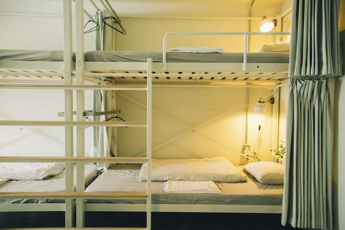 Habitación con literas, ventana, lámpara de noche y cortina.