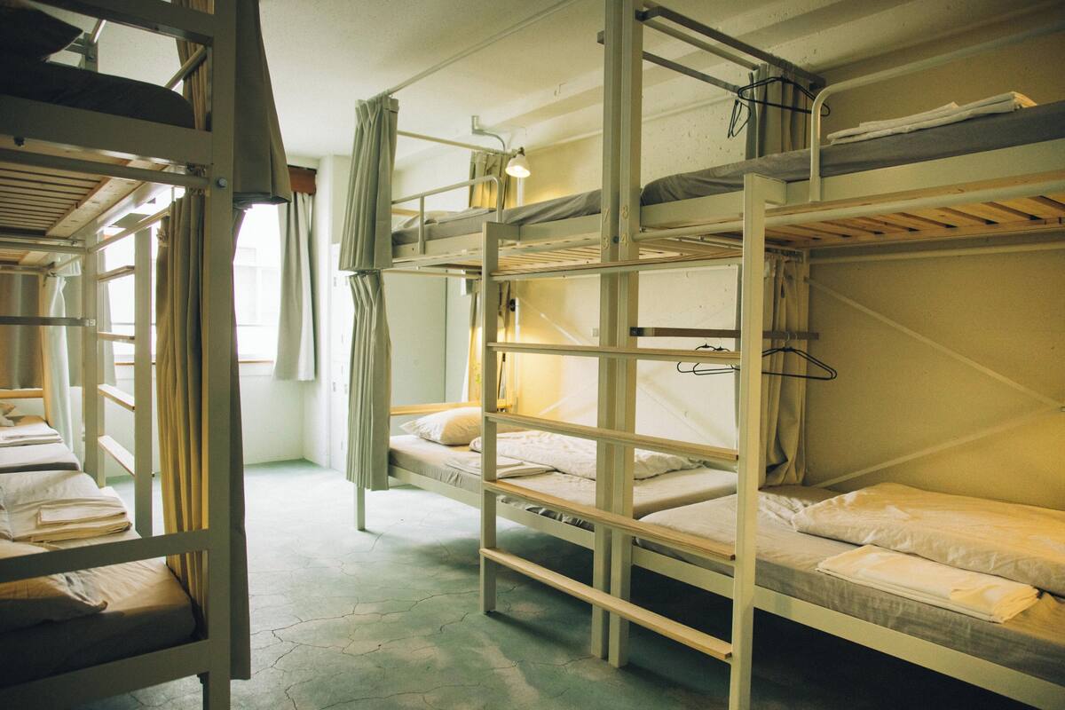 Dormitorio con literas, ventana, cortinas y lámpara.
