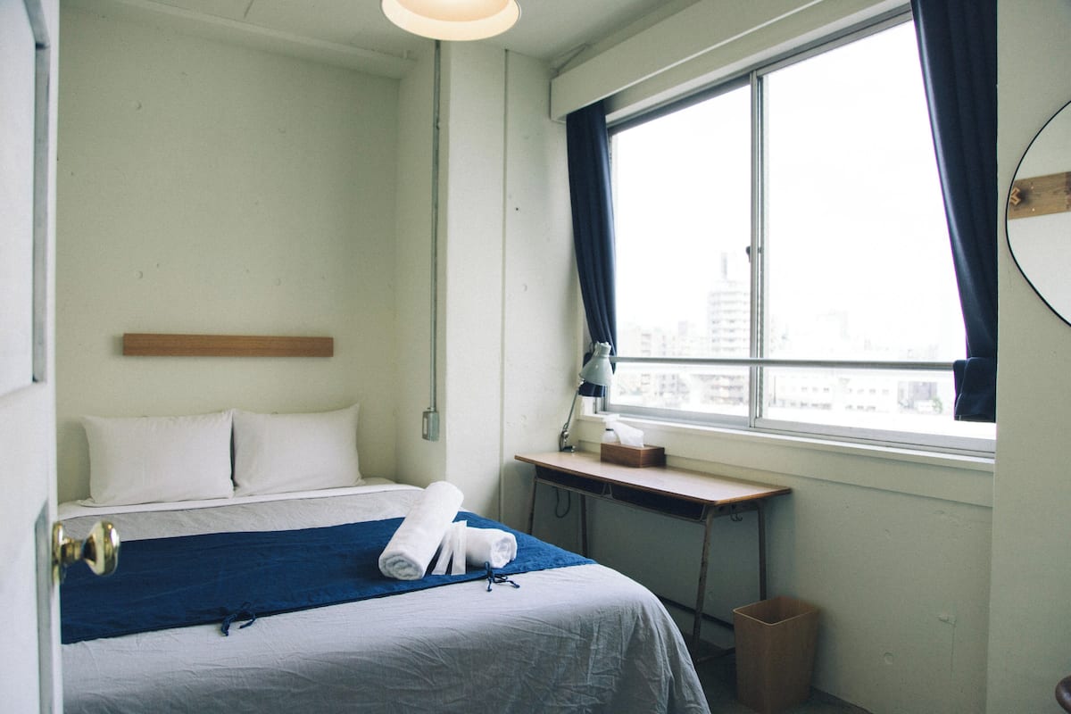 Habitación de hotel con cama, escritorio, ventana con cortinas y vista a la ciudad.