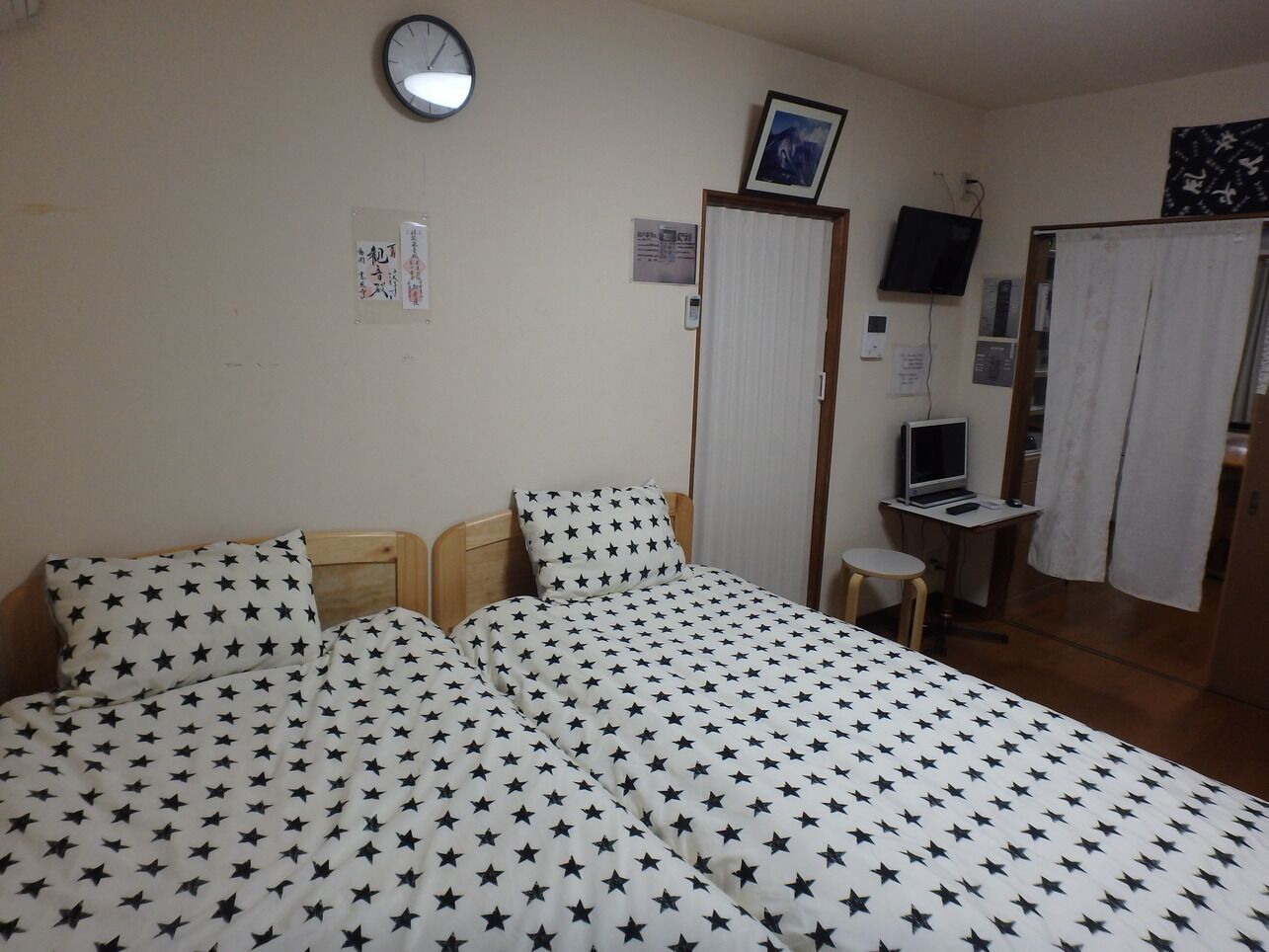 Une chambre à coucher comprenant un lit, un bureau, une chaise, une horloge et un téléviseur.