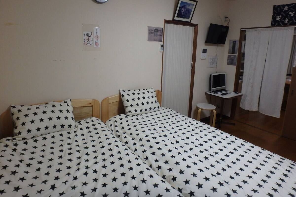 Een slaapkamer met een bed, een bureau, een stoel, een klok en een televisie.