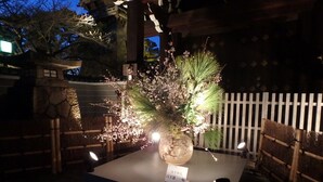 Une lanterne japonaise traditionnelle, ornée d’une composition florale à l’intérieur, posée sur un piédestal en pierre.