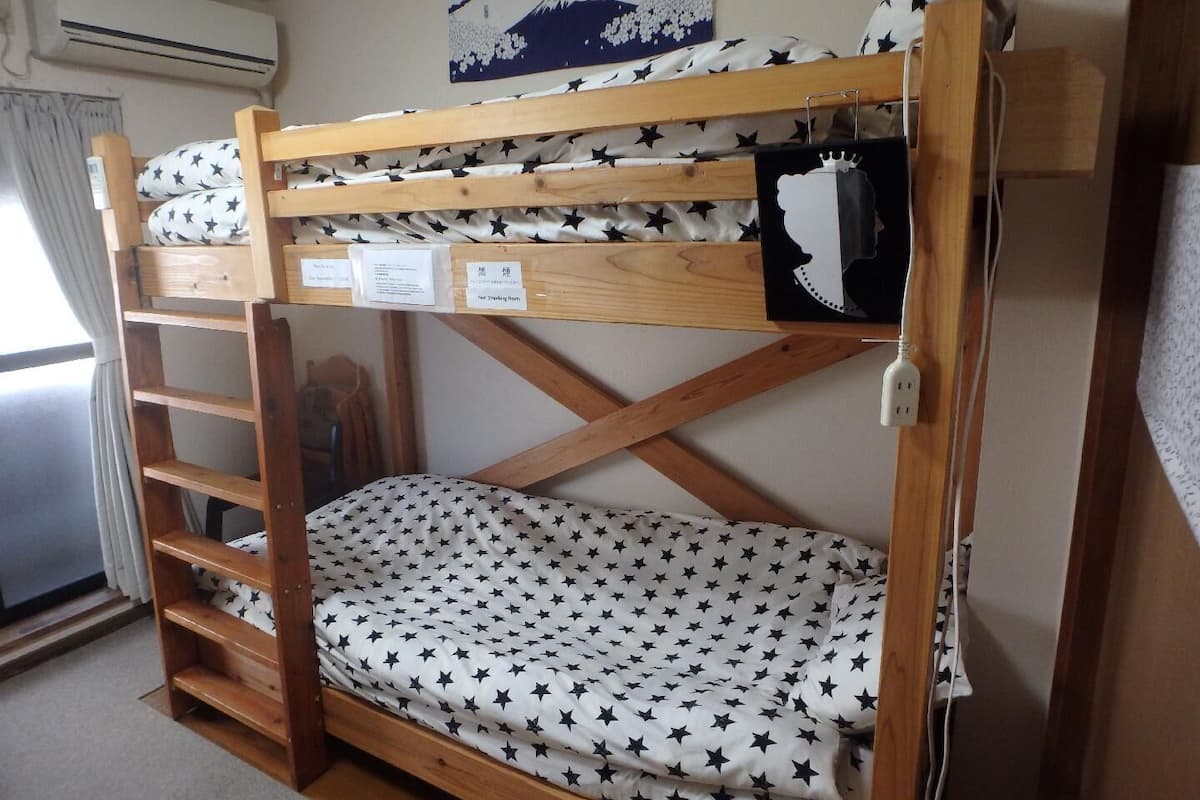 Een stapelbed met een matras met steropprint, een houten ladder en een luchtverfrisser aan de muur.