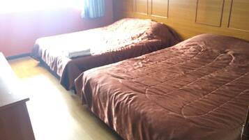 A hotel room with two beds, wooden headboard, and a wooden dresser.