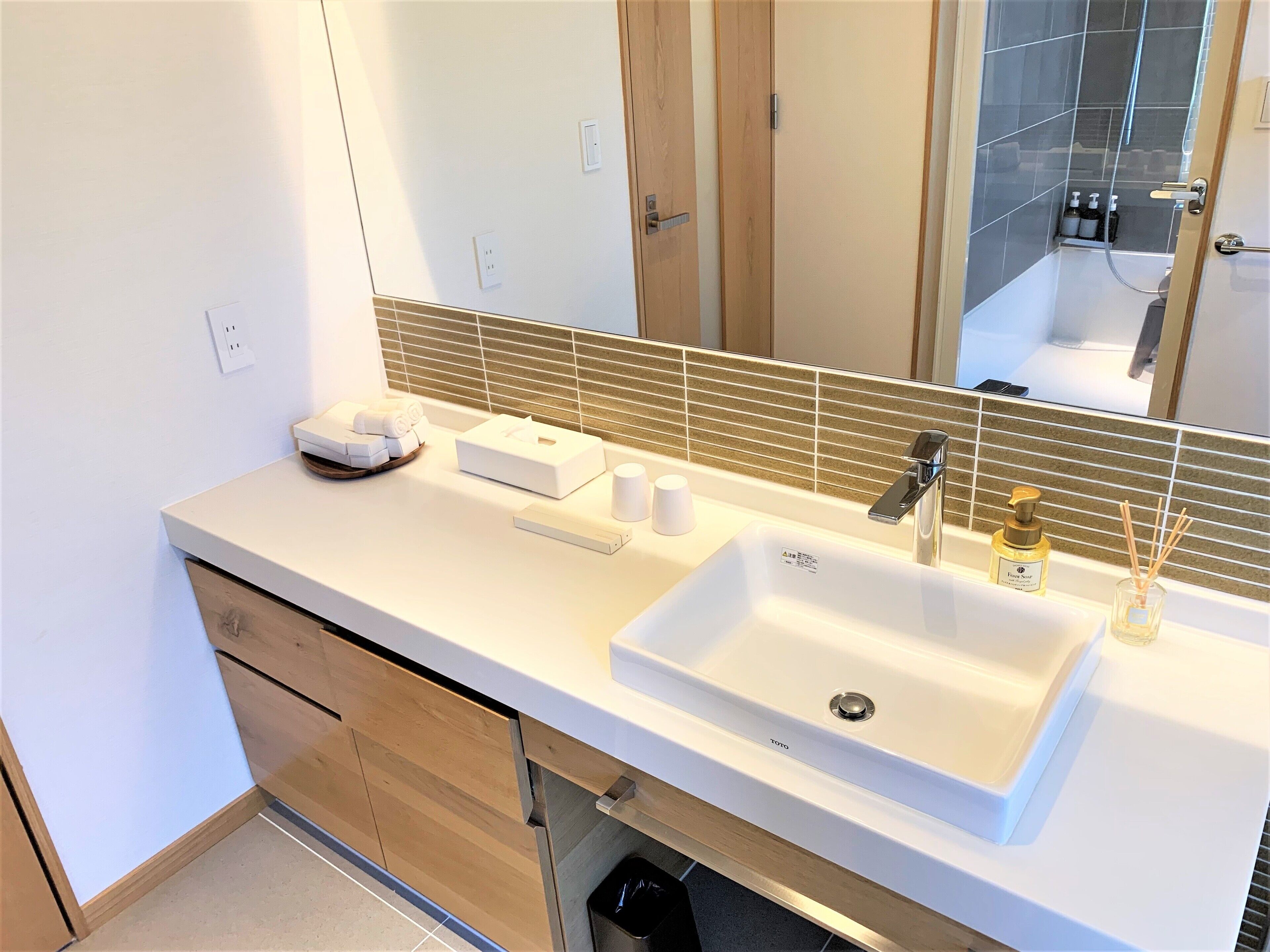 Un baño moderno con un lavamanos blanco, un espejo y un mueble de madera.