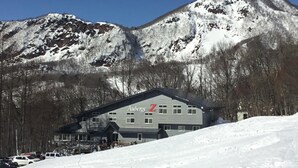 A hotel with a 'Z' logo, surrounded by snow-covered mountains and trees. - Lodge Christmas Rose ZAO (Yamagata)