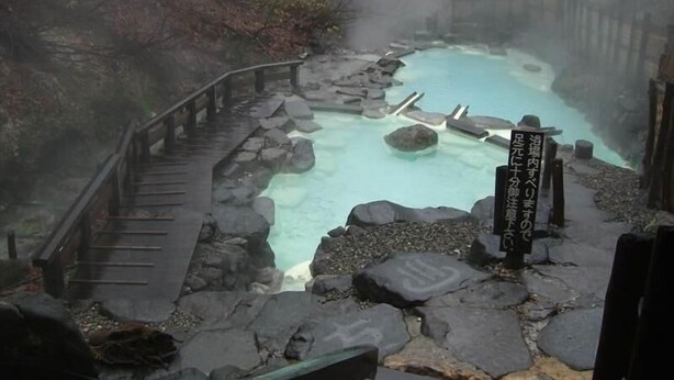 A hot spring area with a wooden walkway and a sign in Japanese. - Lodge Christmas Rose ZAO (Yamagata)