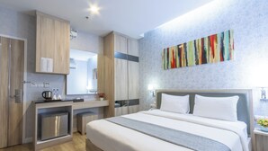 Una habitación de hotel moderna con una cama grande, un escritorio integrado y una pequeña cocina.