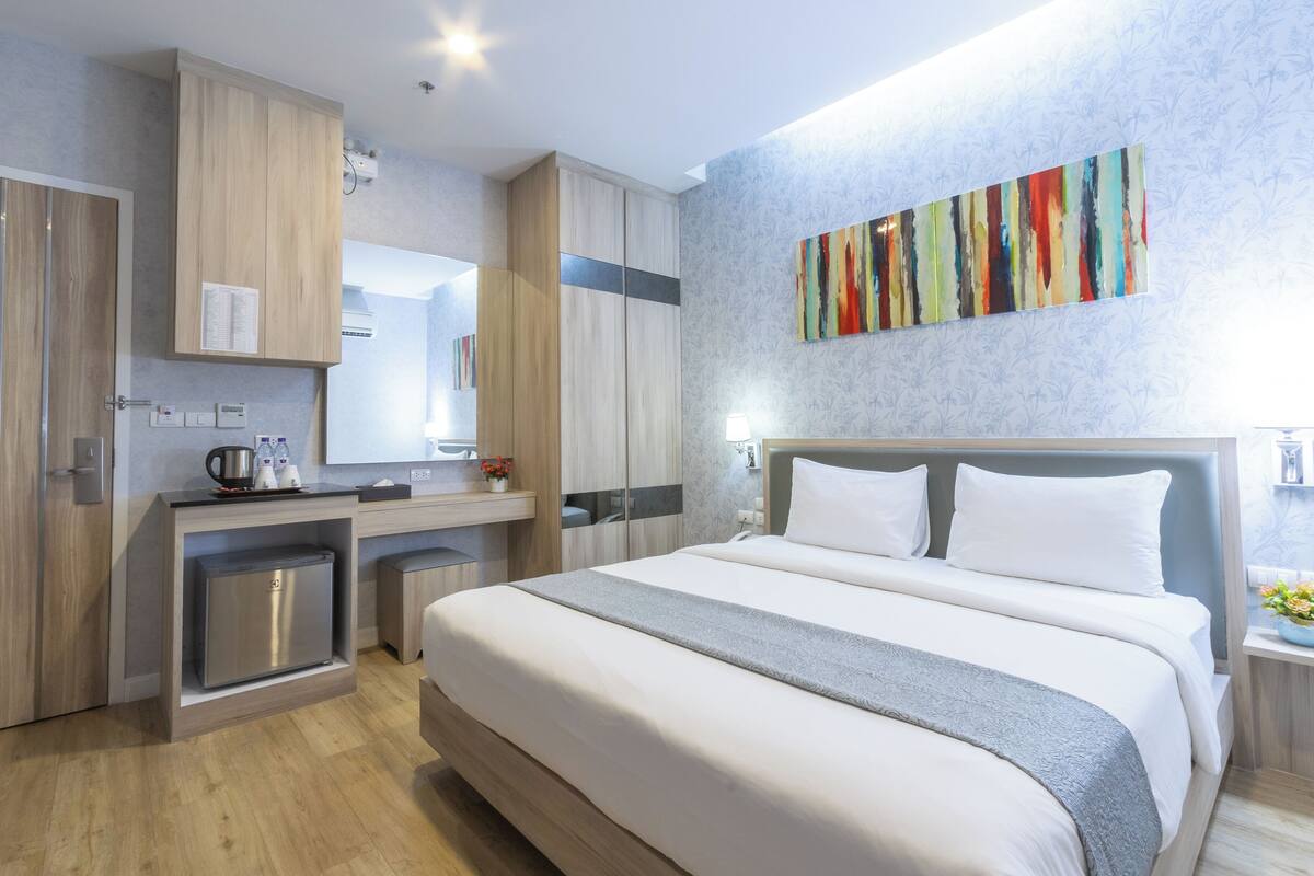 Une chambre d’hôtel moderne dotée d’un grand lit, d’un bureau intégré et d’une petite kitchenette.