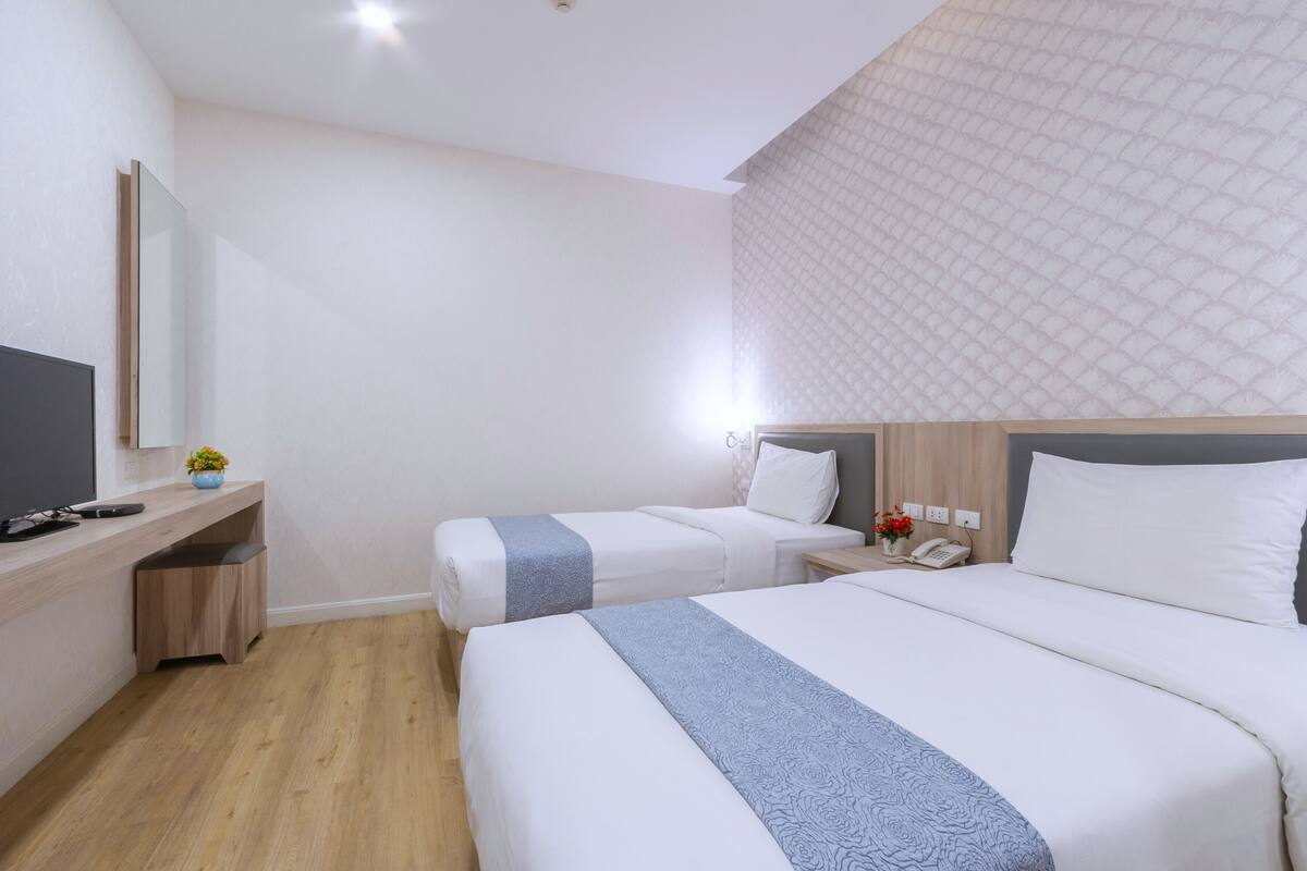 Une chambre d’hôtel avec deux lits, un bureau, une télévision et un téléphone.