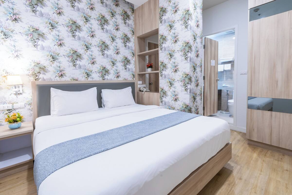 Une chambre à coucher moderne avec un grand lit, une tête de lit en bois et une armoire intégrée.