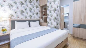 Quarto moderno com cama grande, cabeceira de madeira e armário embutido.