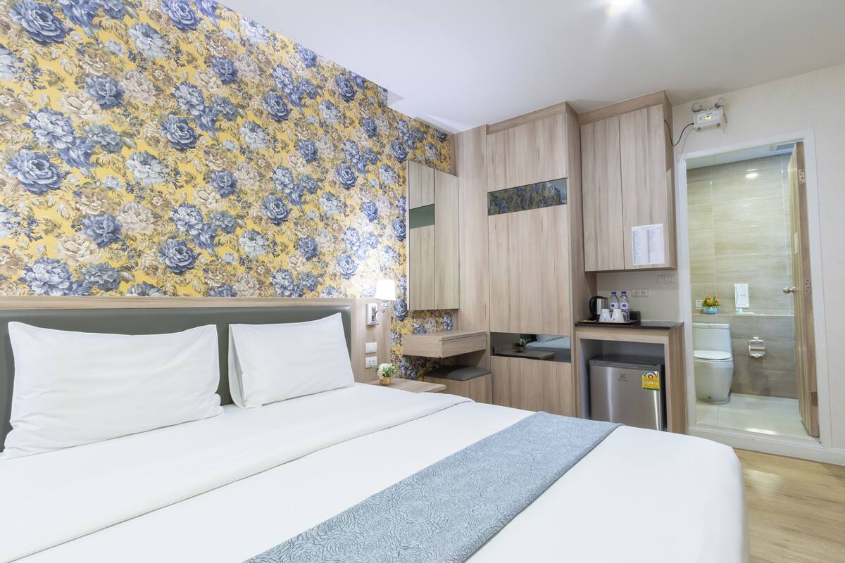 Une chambre d’hôtel avec un lit, un petit bureau, un miroir, une douche et des toilettes.