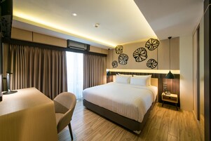 Habitación de hotel con una cama grande, un escritorio y una silla. Decoración en las paredes y una lámpara en el techo.