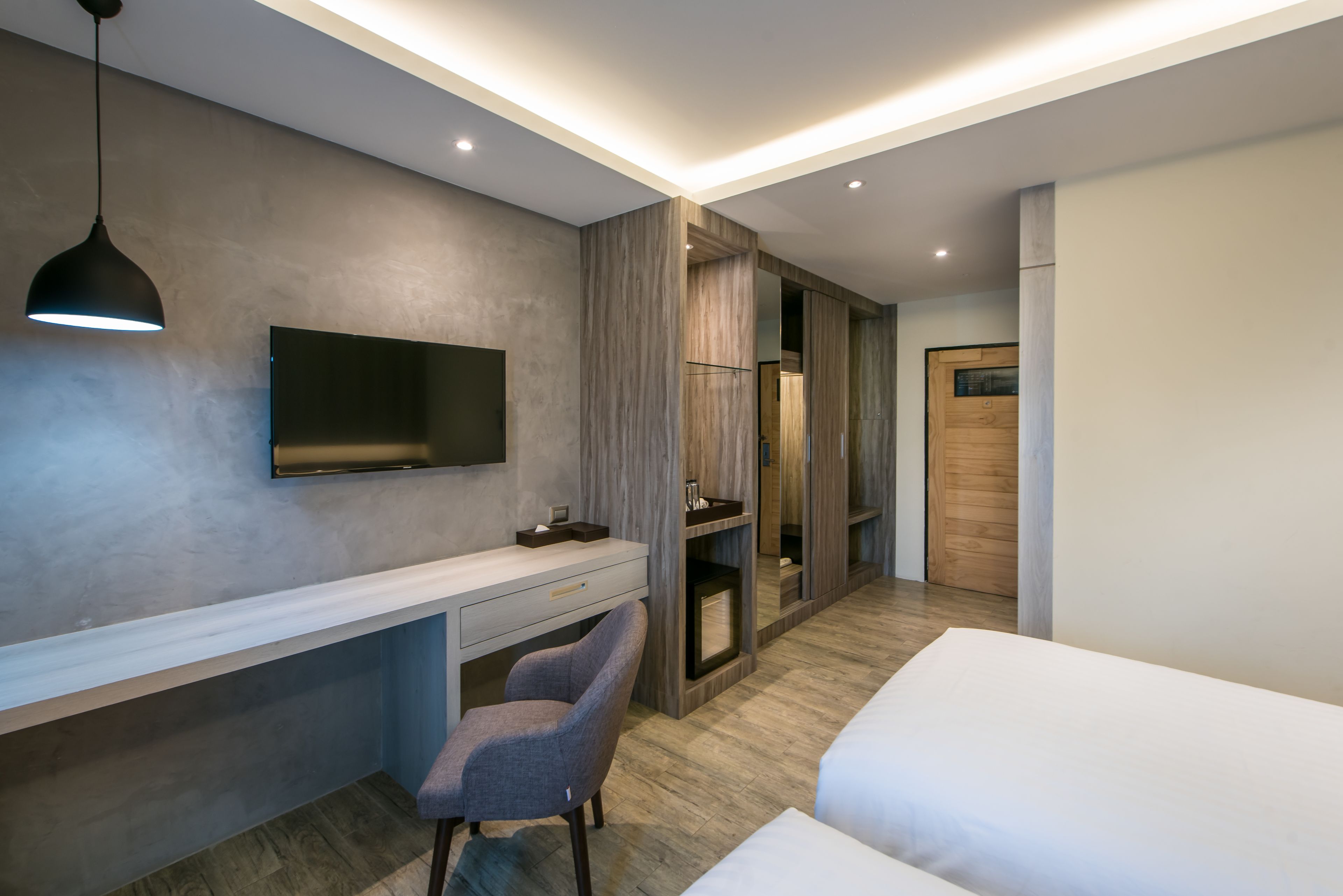 A modern hotel room with a desk, chair, and a bed.