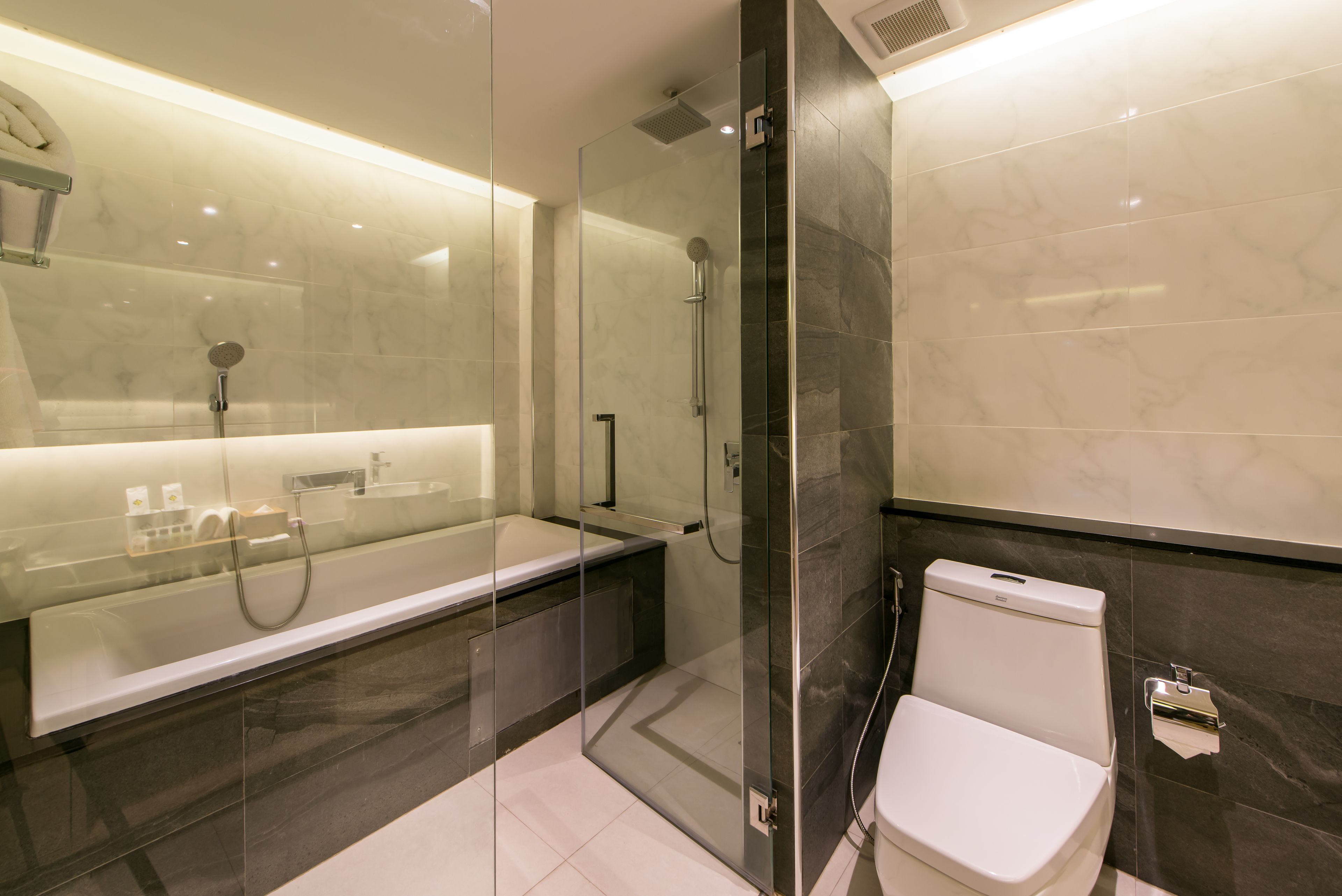 Un baño moderno con ducha envuelta en vidrio, bañera independiente y retrete.