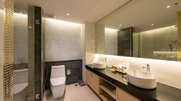 Un baño moderno con un espejo grande, dos lavamanos, un inodoro y una ducha.