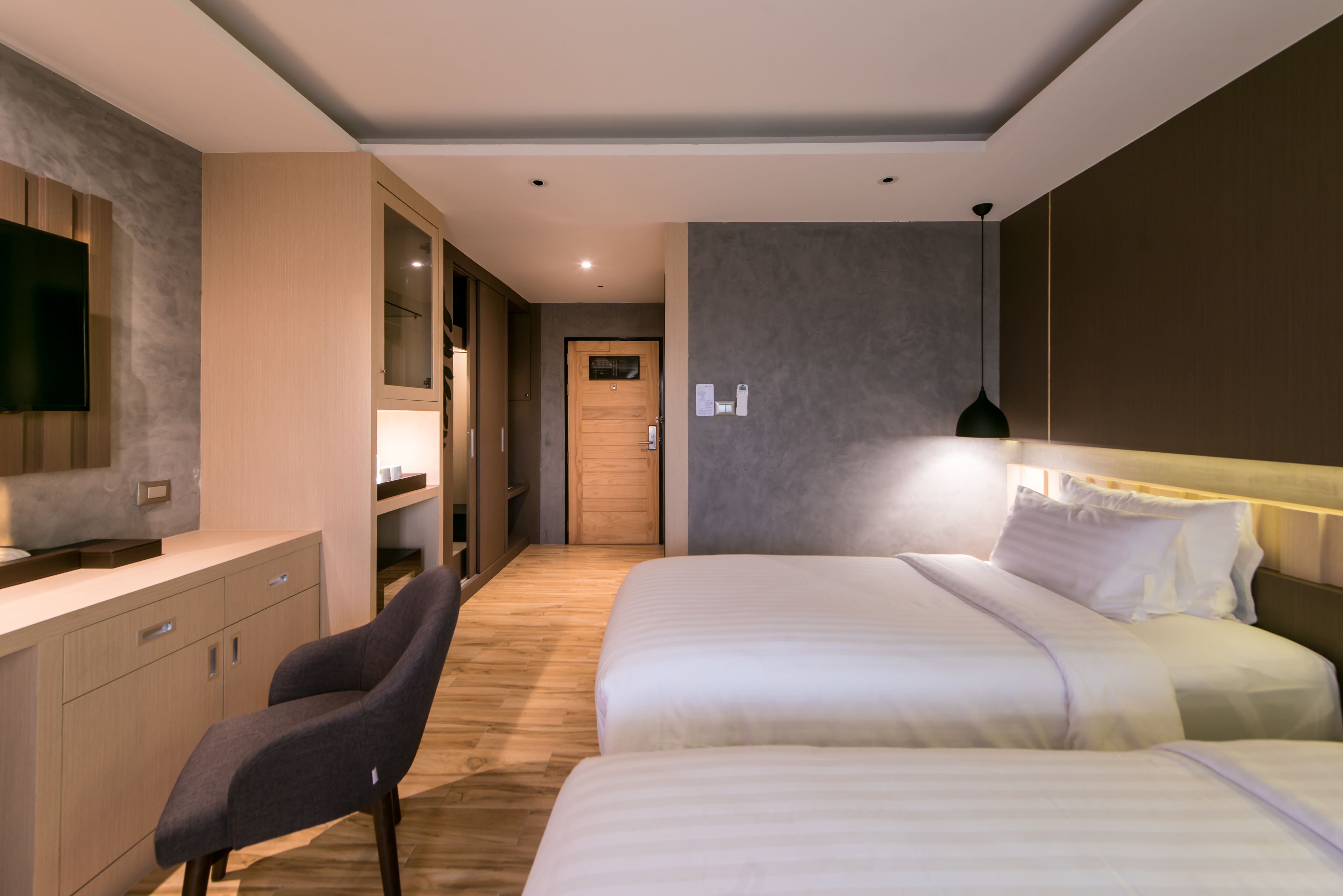 Une chambre d’hôtel moderne avec un grand lit, un bureau avec une chaise, une télévision et une porte en bois.