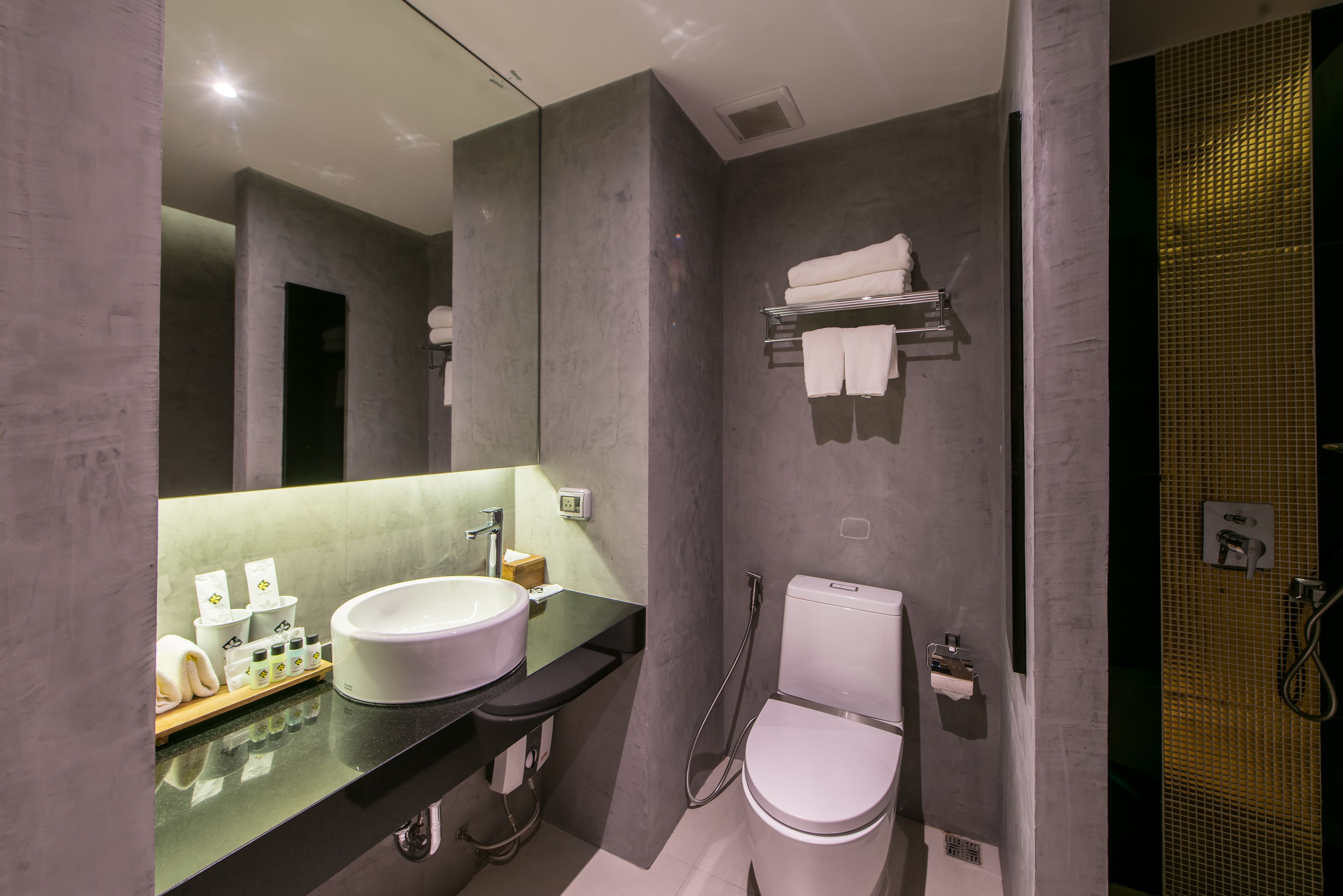 Un baño moderno con un espejo grande, un lavamanos blanco, un inodoro y una zona de ducha.