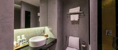 Un baño moderno con un espejo grande, un lavamanos blanco, un inodoro y una zona de ducha.