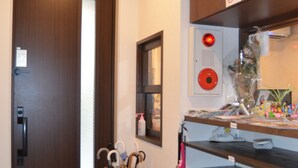 A hotel room with a wooden door, a fire extinguisher, a trash bin, and a shelf with various items. - Fukuoka Guest House Jikka (Fukuoka)