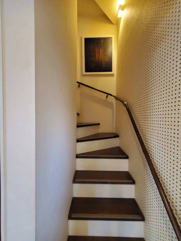 Una escalera con barandilla, un cuadro colgado en la pared y un diseño de pared perforada.
