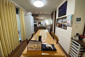 A compact kitchen with a dining area, a refrigerator, a microwave, and a small sink. - Fukuoka Guest House Jikka (Fukuoka)