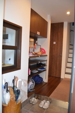 Un couloir avec des armoires en bois, un porte-chaussures et un petit espace de rangement pour les chaussures.