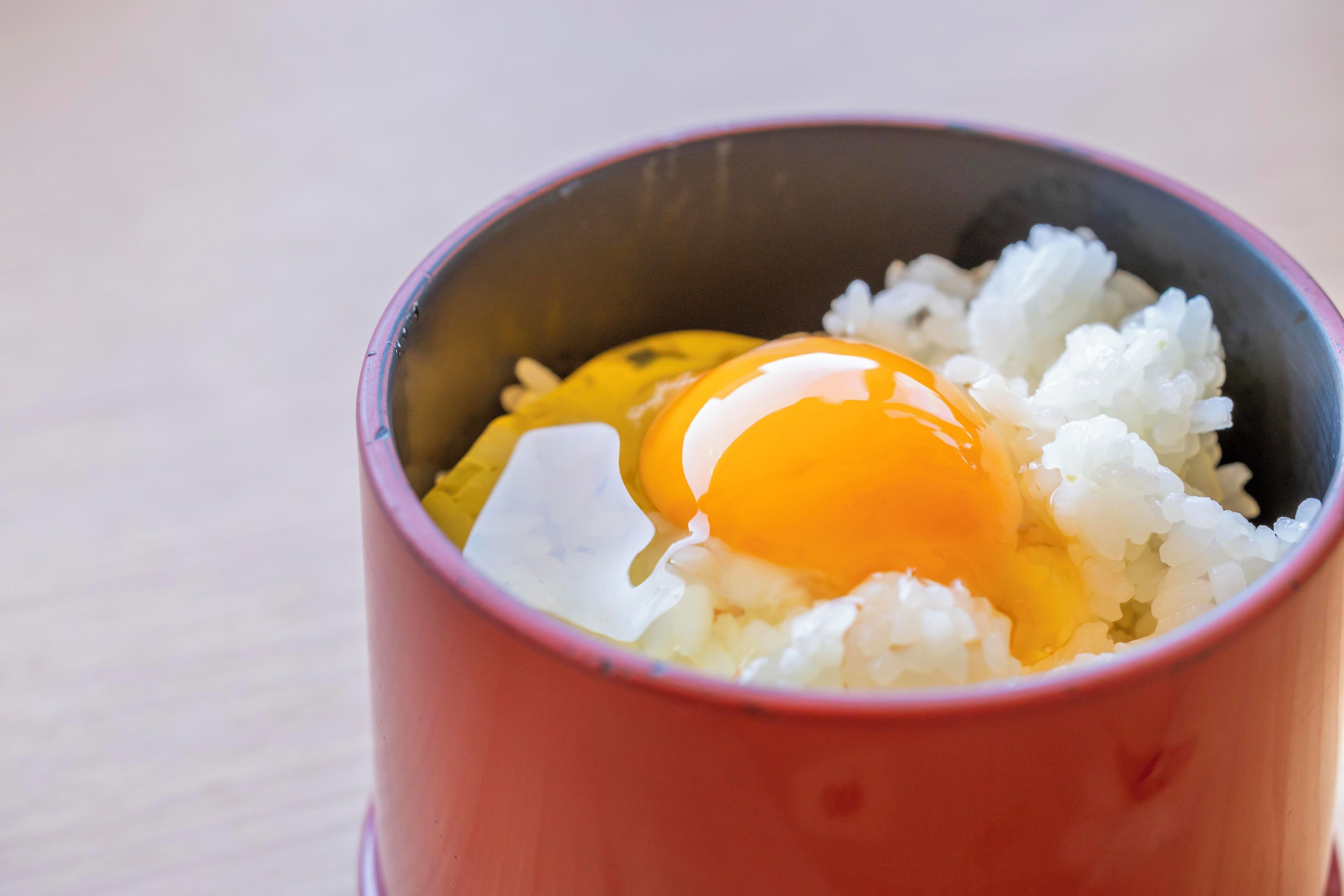 Uma tigela vermelha com arroz branco e ovo cozido, com gema vibrante.