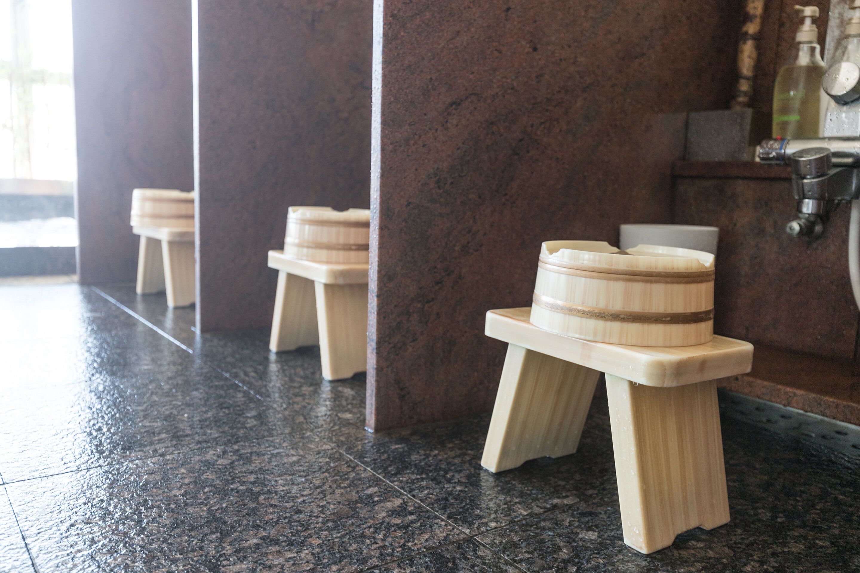 A restroom with wooden stools and a sink.