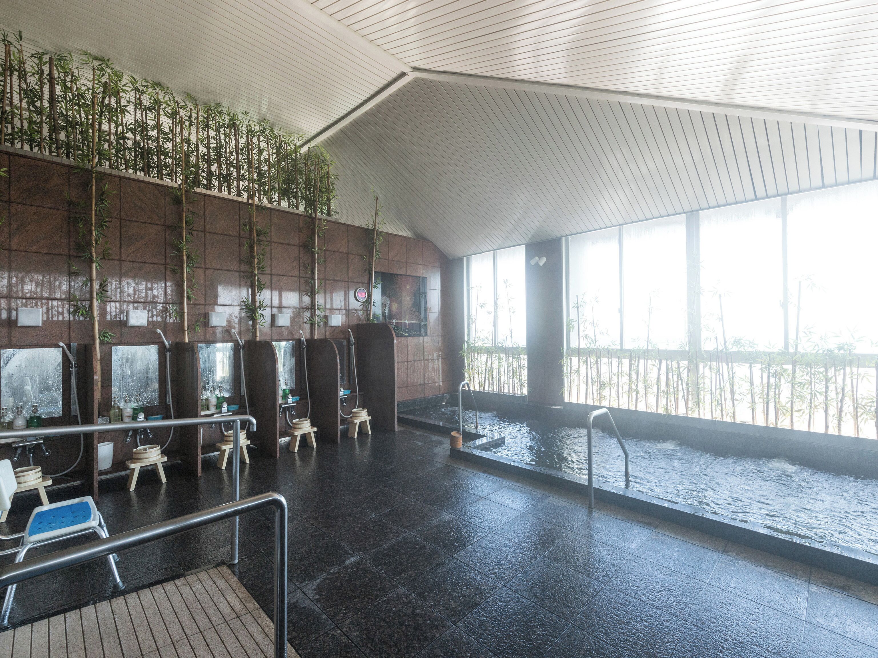 Una piscina interior con múltiples zonas de duchas, suelo de baldosas y vistas al agua.