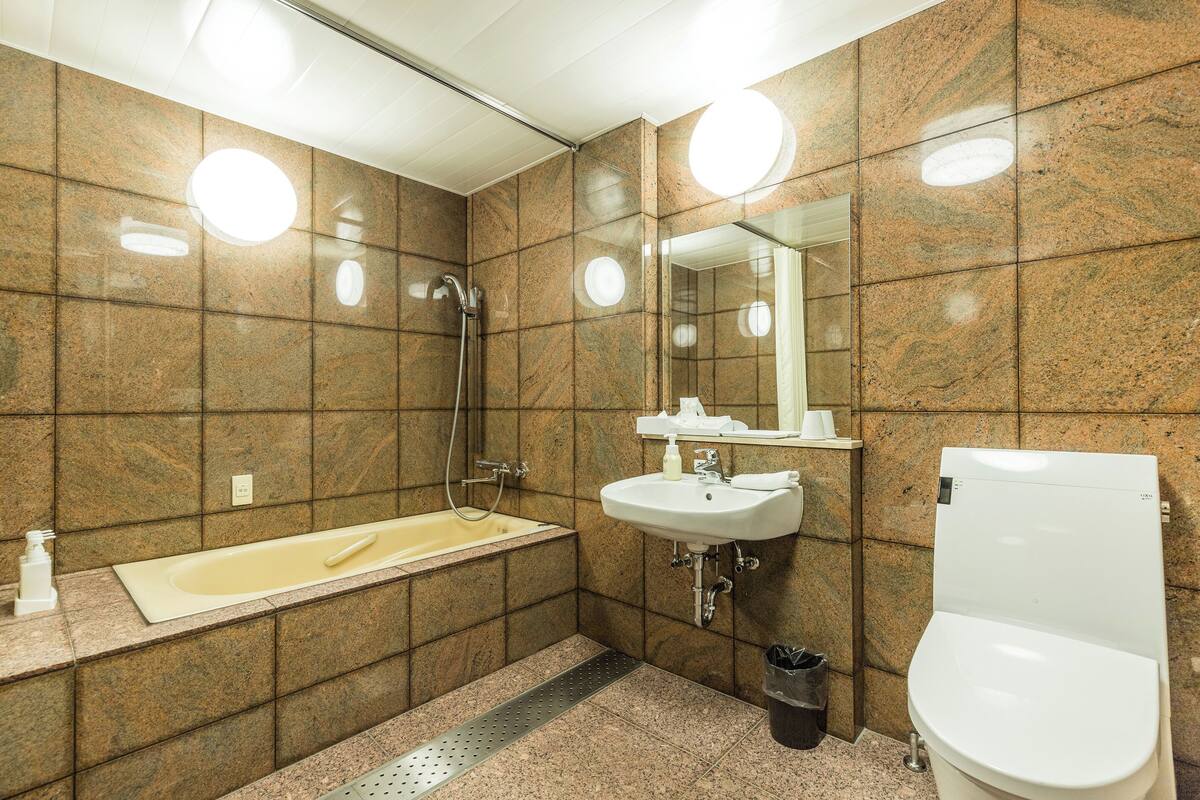 A bathroom with a bathtub, sink, mirror, and toilet.