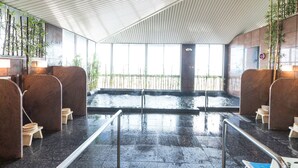Un espace spa moderne doté d’un sol carrelé, de cloisons en bois et d’une vue sur un jardin de bambous.