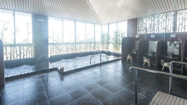 Un espace piscine intérieur moderne, avec vue sur des bambous à l’extérieur, un sol carrelé et un plafond en bois.