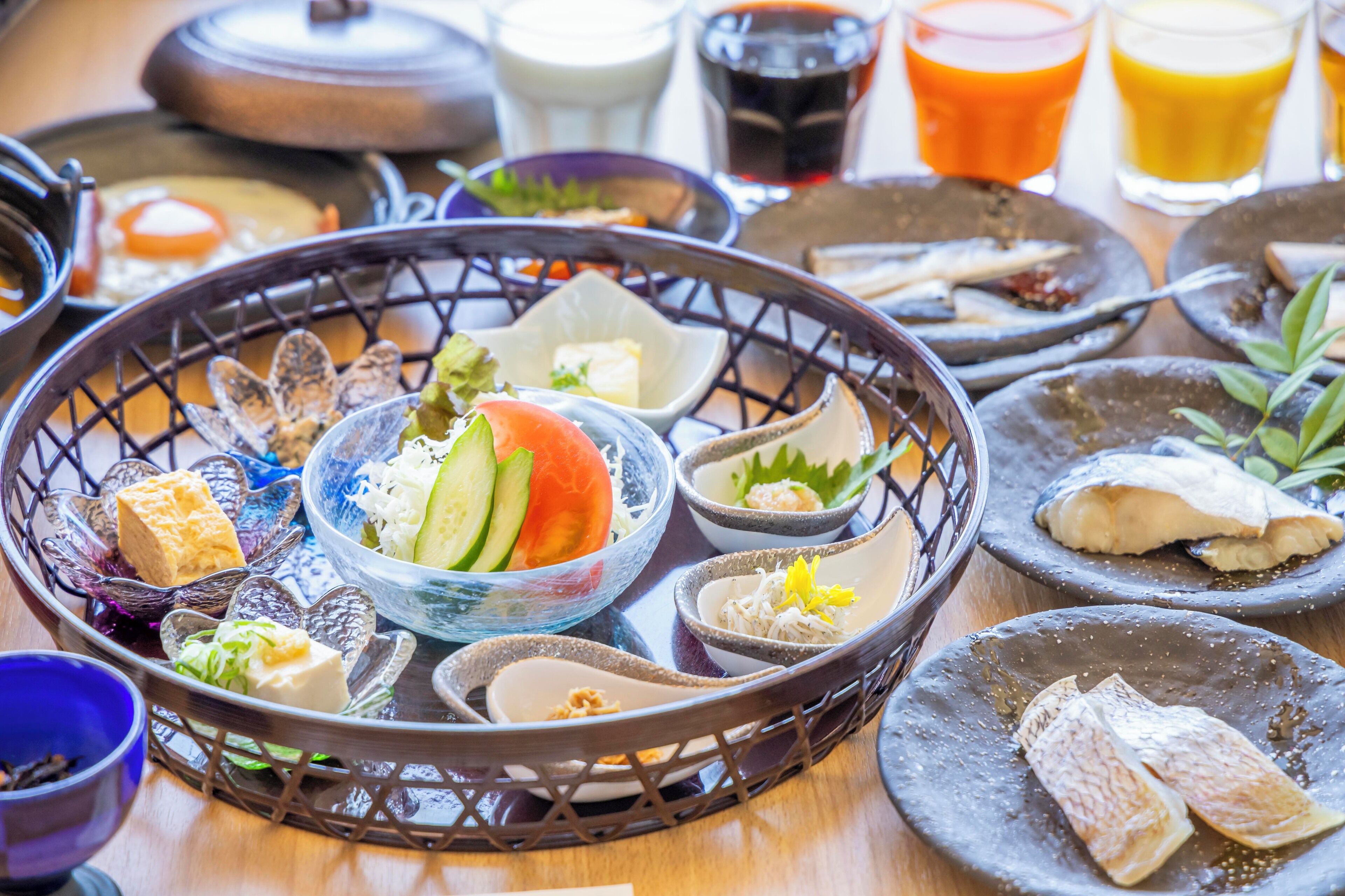 A variety of dishes and drinks on a tray, including fish, vegetables, and possibly tofu.