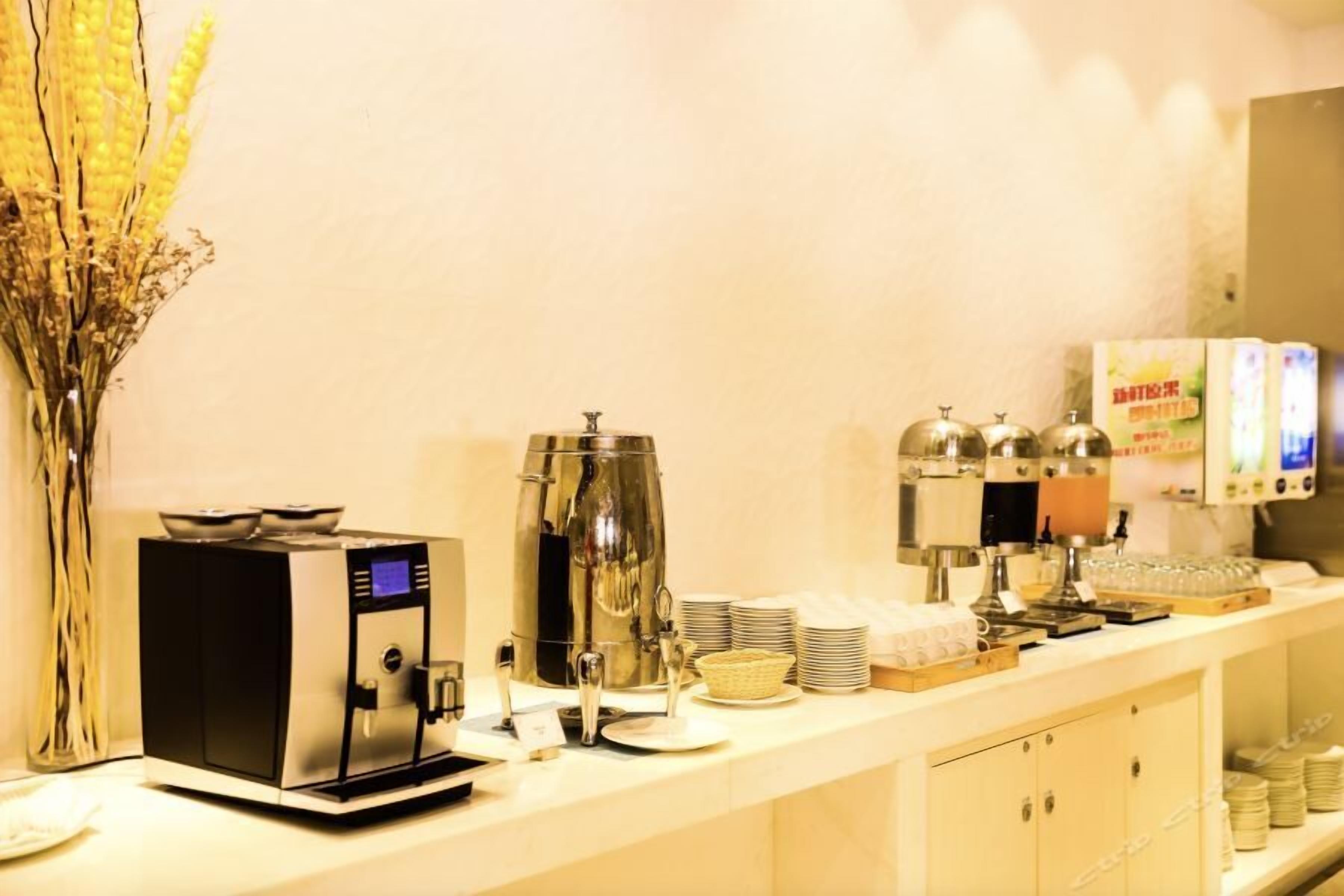 A buffet setup with a coffee machine, a large urn, and stacked plates.