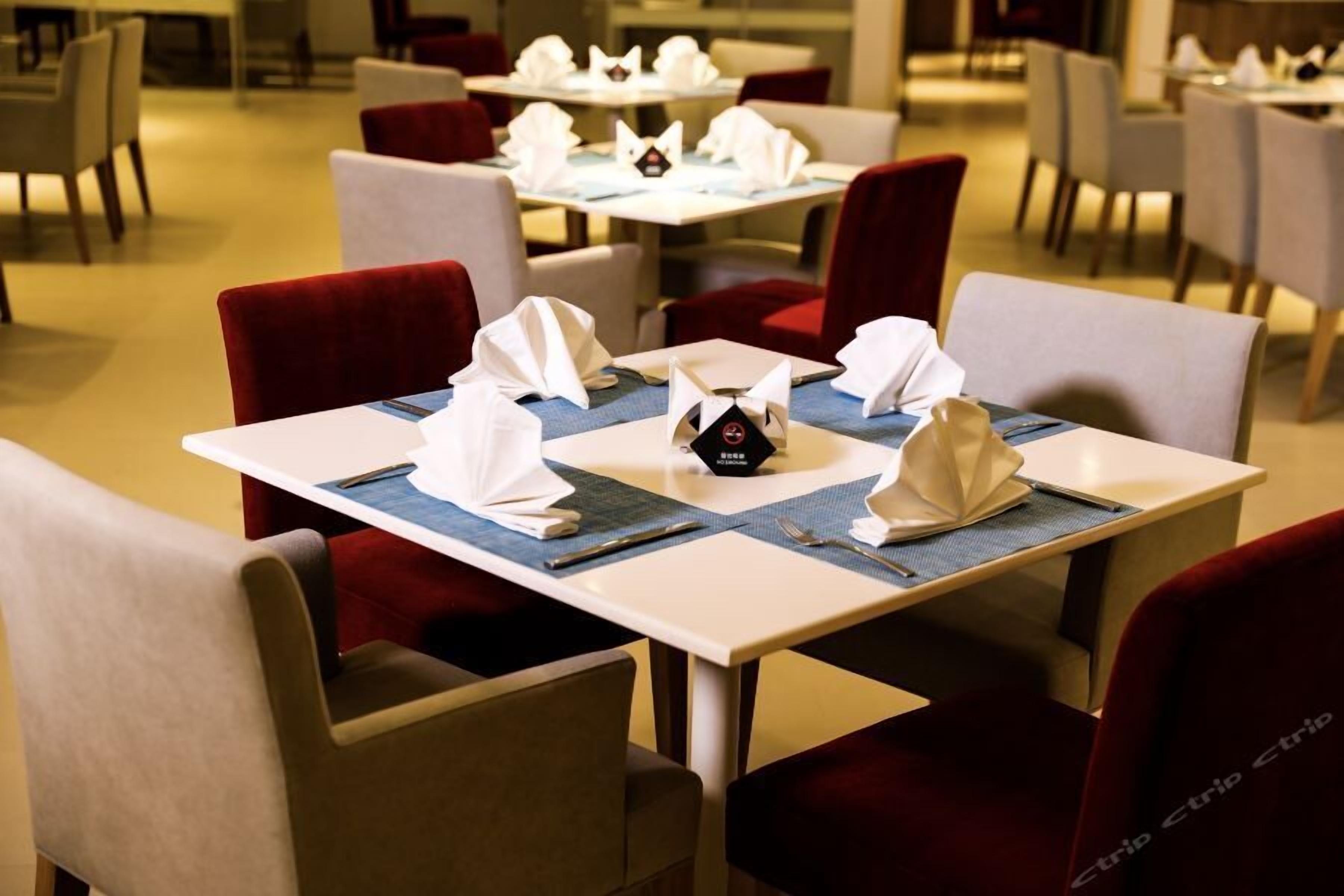 Comedor con mesas dispuestas para cuatro, cada una con un mantel individual, servilletas dobladas y un pequeño adorno.
