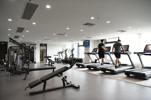 A gym with treadmills, weight machines, and a bench.