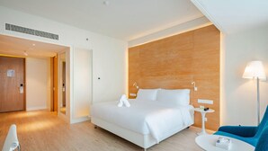 Camera d'albergo con un letto grande, un tavolino, una poltrona blu e una parete d'accento in legno.